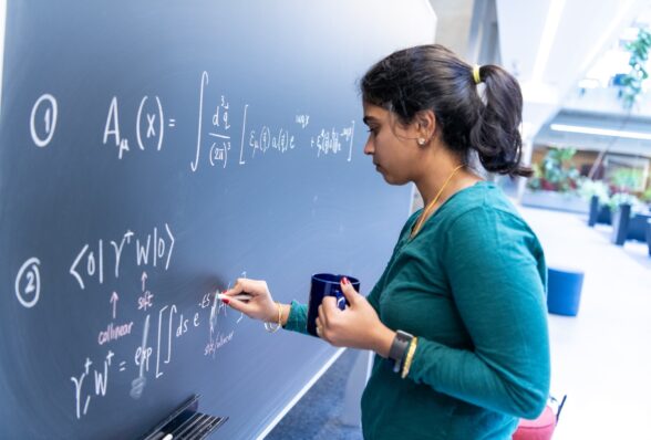 woman with coffee cup writing at black board