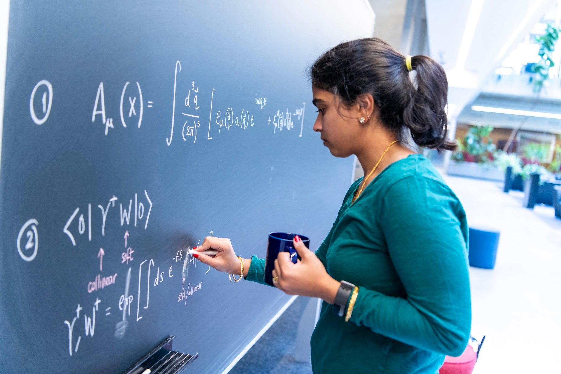 woman with coffee cup writing at black board